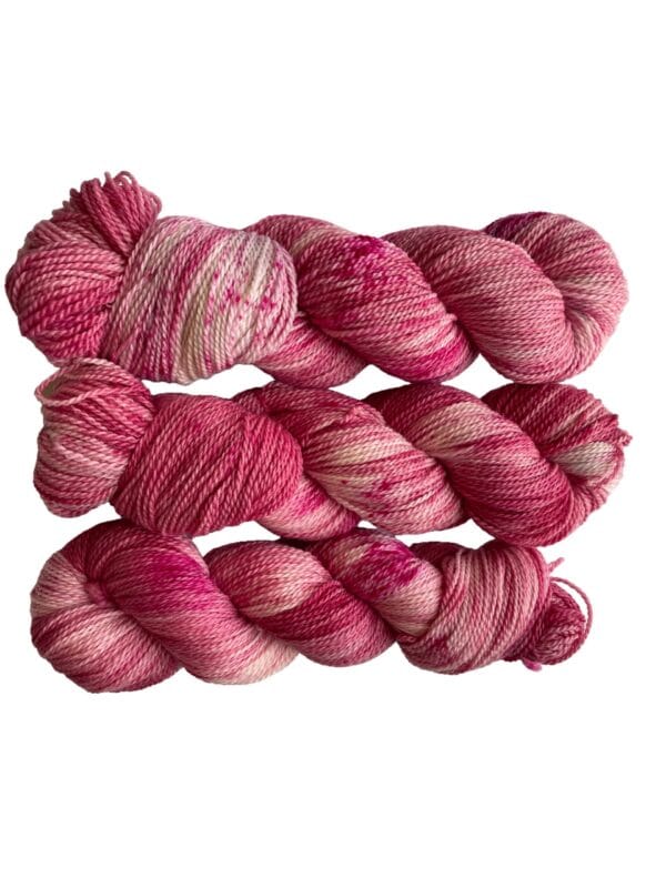 Hand dyed superwash Merino and bio nylon sock weight yarn. Warm pink and white with fluorescent speckles.