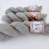 img_985d0acdd3b8.jpg Leigrijze strengen 4-ply garen met S7oRS Atelier-labels op een witte ondergrond.