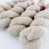 img_ba9468d94bf4.jpg Close-up of light beige, plied skeins of 4-ply yarn on a white background.