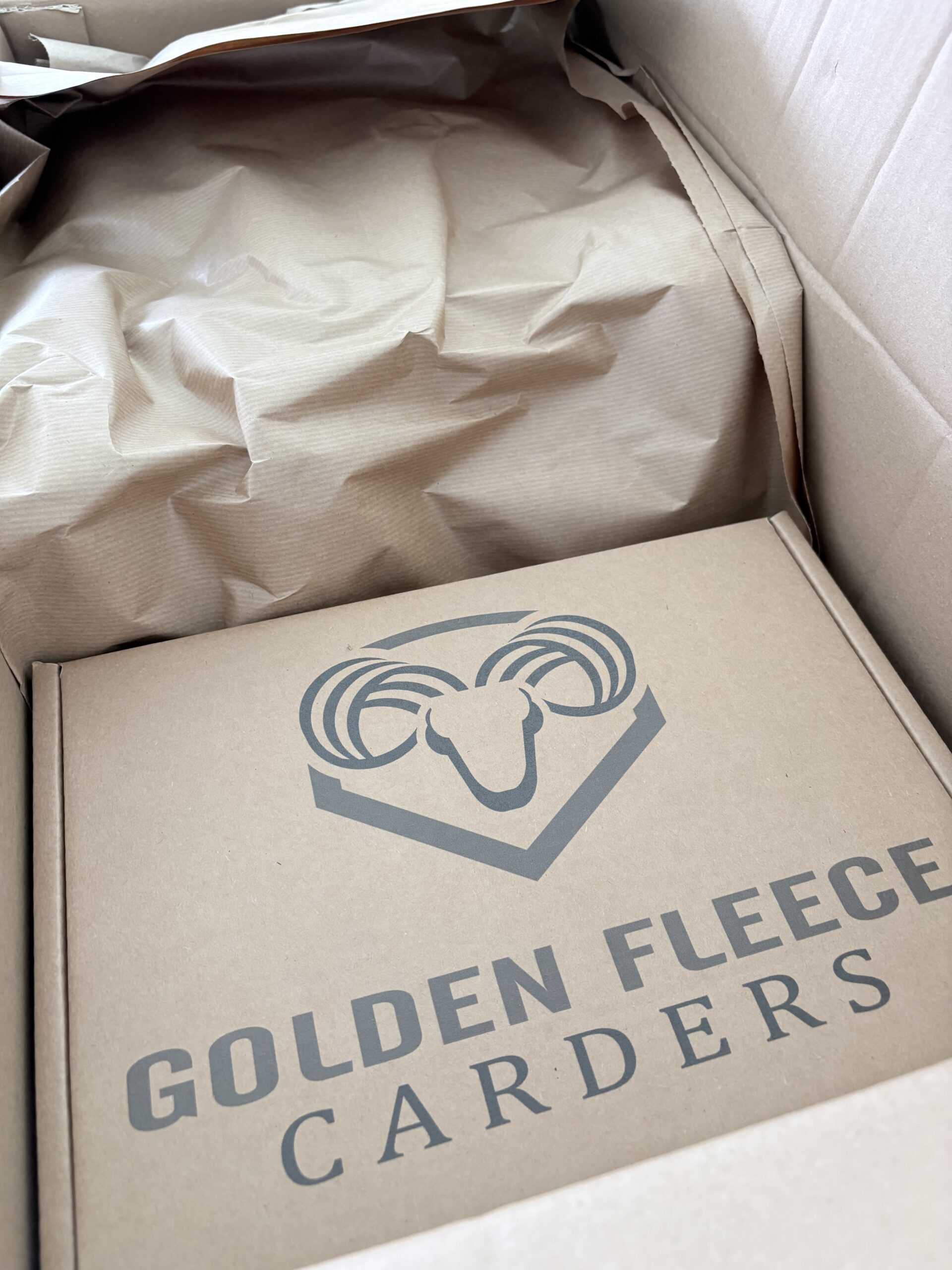 Open doos van Golden Fleece Carders met beschermend papier en deksel.