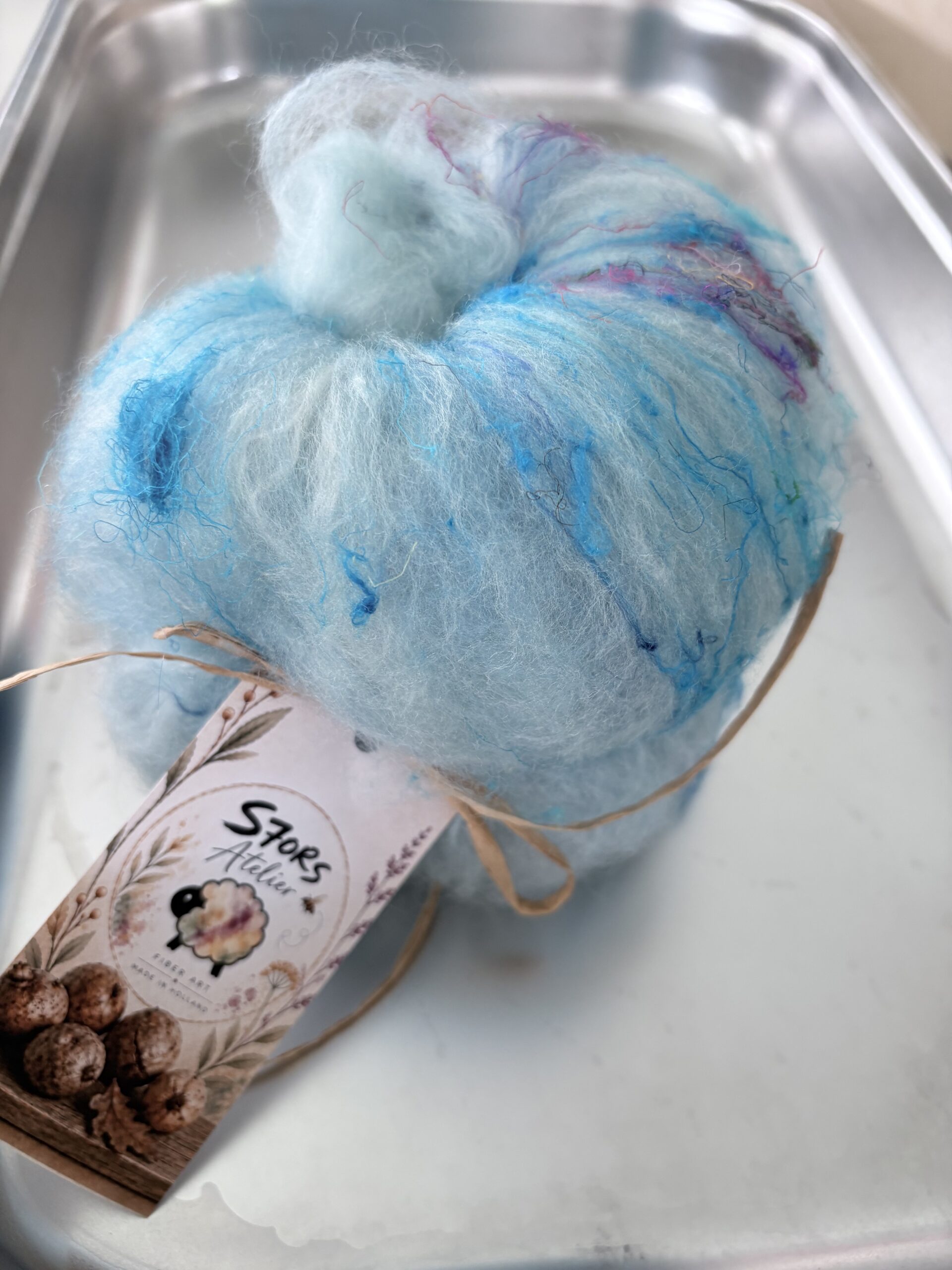 Blauw-witte S7oRS Art Batt met gekleurde vezels in een metalen bak.