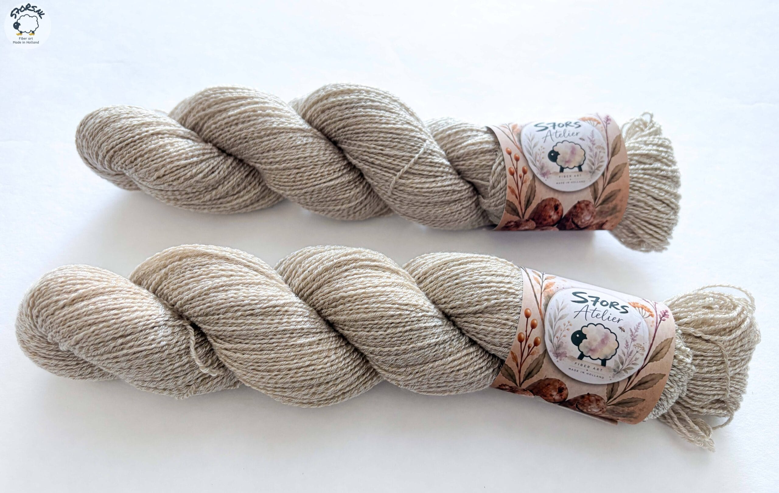 Twee lichte geverfde strengen garen met S7oRS Atelier-labels op een witte ondergrond.